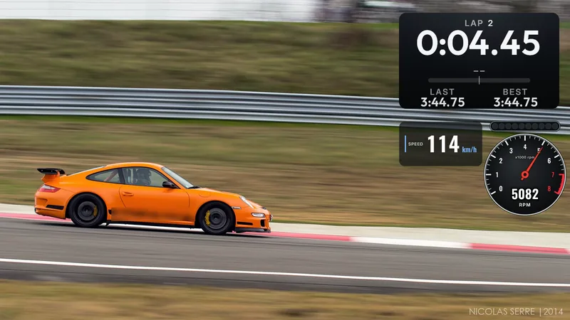 A photo of an orange sports car on a race circuit; lap time top right (lap 2, 0:04.45, last and best 3:44.75), speed (114 km/h) and a race rev counter with shift lights (5082 rpm) below it.